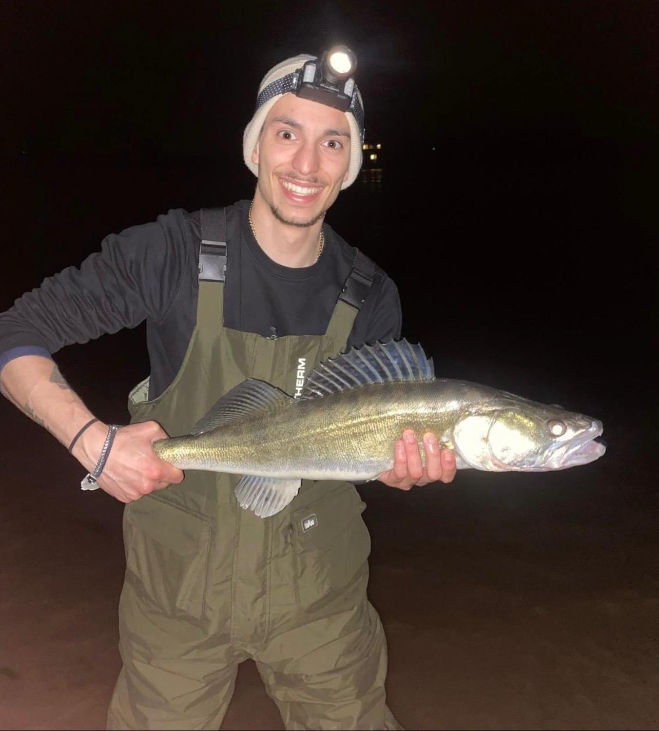 Angler mit Stirnlampe und Zander bei Nacht
